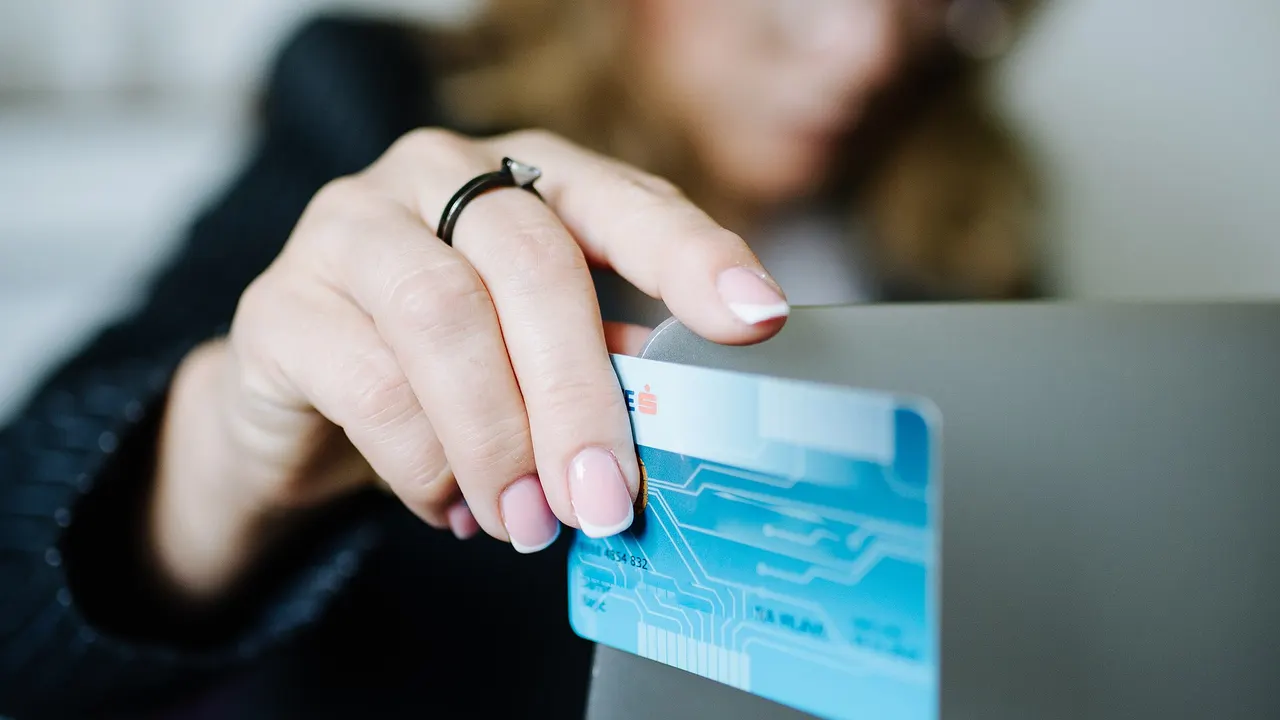 A person holding a credit card while using a laptop at home to make an online purchase